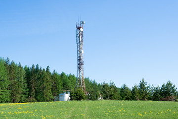 Cellular repeater tower on blue sky background. Spring landscape.