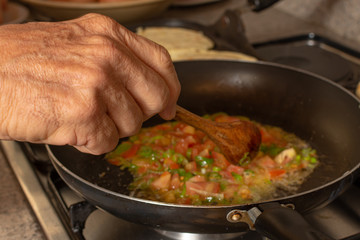 Green onion and tomatoes chopped on a cast iron. Home made colombian hogao or criollo sauce