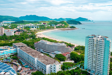 Naklejka premium Hainan Island. Views of the city of Sanya and Dadonghai Bay from above. Beautiful top view of South China Sea. Tourist Center of Dadonghai Bay. Palm trees and green plants everywhere.