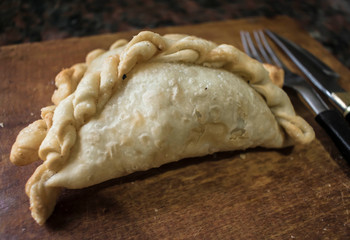 Argentine fried empanadas, served on wooden board.