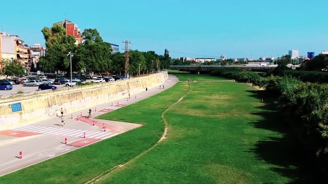 Drone flying over besos park in barcelona with people running, biking.