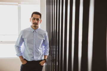 Fototapeta premium Young businessman asian looking at camera. Portrait of a happy handsome young man in office. Young cool trendy man looking at camera.