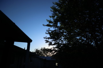 house at sunset with clear blue skies with the hint of yellow and orange as well with some trees