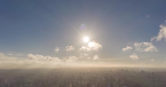 Aerial hyperlapse of the sun with clouds and camera on tilt down showing the city