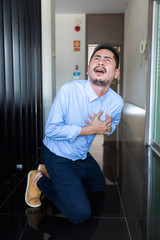 Young Businessman holding his heart in pain while in workplace.