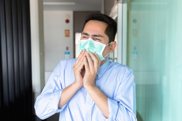 A asian man wearing mask a face prevent the spread of the Covid-19 virus while coughing, sneezing in workplace.