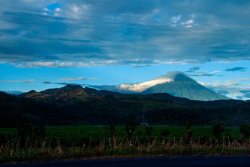 Fototapeta premium Volcano covered with clouds in Guatemala, forest landscape at imposing sunset on the horizon.