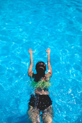 Sexy girl swimming on a big and blue pool under the sunlight in a sunny day 