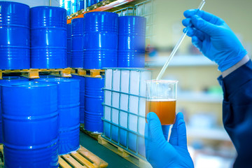 Chemical research at the enterprise. A chemist holds a container of chemical liquid against a...