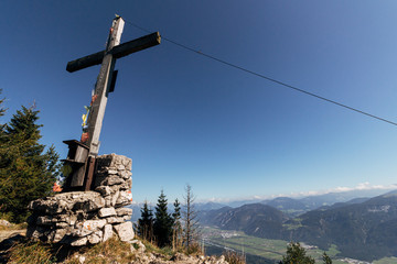 Cross at the top of a hiking trail on the outskirts of Brandenberg with the Inntal valley visible in the distance. Tyrol, Austria