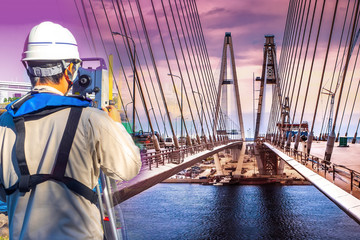 A man looks through the theodolite at the bridge. Checking the bridge structure. Measuring tool for...