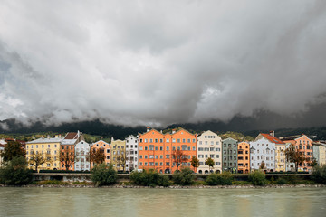 view of Innsbruck with colorful houses along Inn river and famous Austrian snowy mountains in the background, Tyrol, Austria