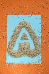 Letter A made from pasta letters on a bright blue and orange background. Baby pasta. Pasta letters.