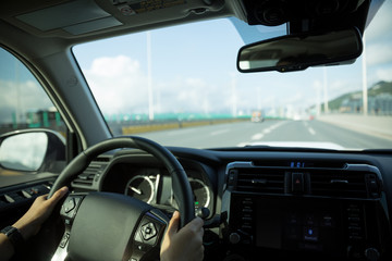 People hands holding steering wheel while driving car on highway road