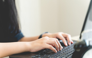 Close up hands of a woman typing the keyboard during work from home. Female programmers are...