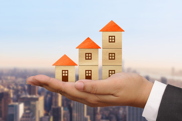 Wood block houses in a growth real estate concept on the businessman’s hand.