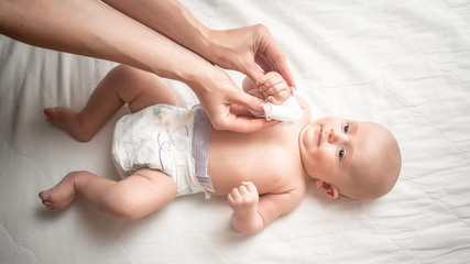 Changing nappies for an adorable little newborn baby. Mother Wiping Baby's Face. Concept Hygiene...