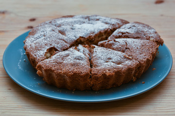 homemade cake with icing sugar on a plate on a wooden table