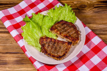 Plate with roasted steaks and rosemary twigs on a wooden table