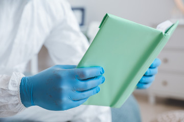 Man in biohazard suit reading book at home, closeup