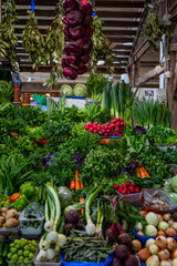 Fototapeta na wymiar A market stall with herbs and a variety of fresh vegetables. Healthy eating and vegetarianism. Front view. Vertical.