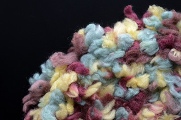 Fragment of a crocheted circle from melange threads based on a plastic canvas on a black background close-up