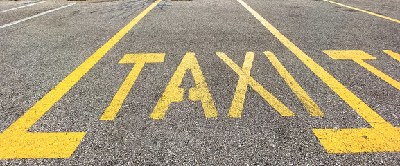 Yellow taxi sign painted on the asphalt street