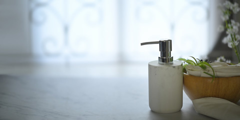 Pump dispenser bottle putting on marble texture surrounded by wooden bowl, pine cone, tree branch, napkin and calico. Bathroom and spa equipment concept.