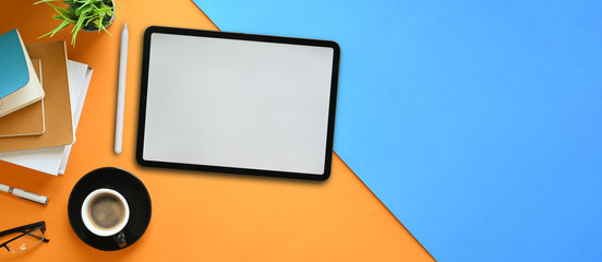 Top view image of white blank screen computer tablet with stylus pen putting on two tones colorful...