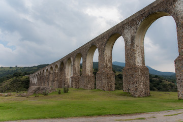Obraz premium Aqueduct Los Arcos Tepotzotlán, Mexico October 07 2018 A wide arched passageway in the back of the complex leads to the extensive gardens area of more than 3 hectares, filled with gardens,