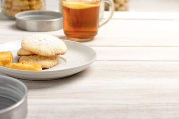 Food concept image with lemon butter cookies and a glass of lemon tea on rustic white table.