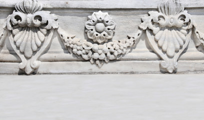 Ancient carved ornament with flower garland on a stone wall