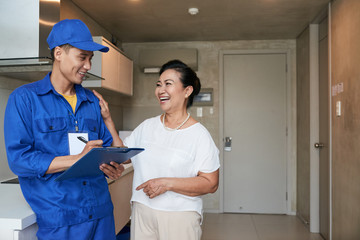 Happy senior Vietnamese woman thanking service worker for fixing problems in her apartment