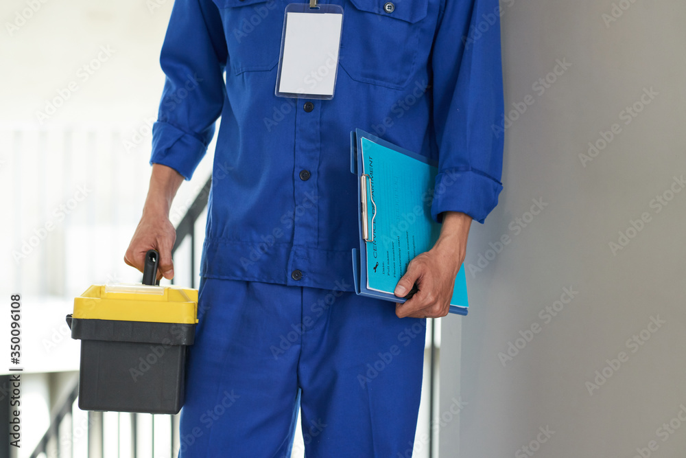 Wall mural cropped image of service worker in blue uniform holding contract and toolbox