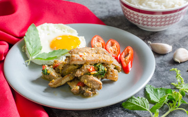 Thai stirfried pig with fried egg ready rice and basil with raw materials are basil leaves red chili and garlic. still life image. thai food concept