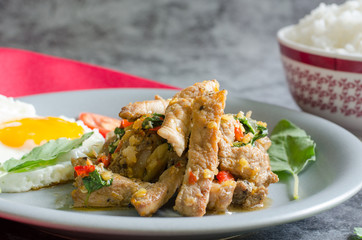 Close up,thai stir-fried pig with fried egg, ready rice and basil with raw materials are basil leaves, red chili and garlic. still life image. thai food concept.