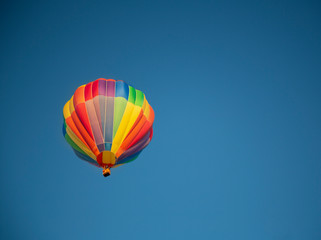 Fototapeta premium Isolated skyward view of a colorful hot air balloon against clear blue sky 