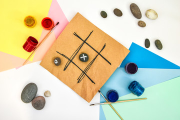 top view of tic tac toe game with stones marked with naughts and crosses. Children's art project, a...