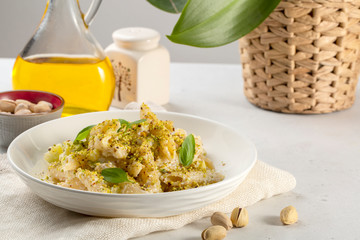 Home made sicilian  ricotta cheese and pistachio pasta, with zucchini and basil leaves. Light table.