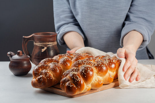 Woman hands covering the homemade Challah -  special bread in Jewish cuisine.Main ingredients are eggs, white flour, water, sugar, salt  and yeast. Decorated  with sesame and poppy seeds.