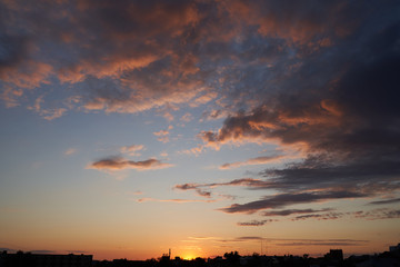 A beautiful evening blue sky at sunset with flaming bright light clouds. Warm evening.