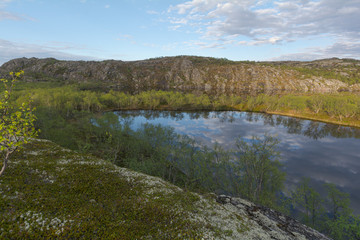 The reservoir is surrounded by hills and forest.Clouds are reflected in the water.Summer landscape.