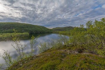 The reservoir is surrounded by hills and forest.Clouds are reflected in the water.Summer landscape.