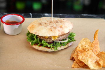 Burger with meat and vegetables. Double cheese burger. Hot burger in a burning sauce. 