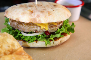 Burger with meat and vegetables. Double cheese burger. Hot burger in a burning sauce. 
