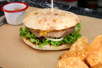 Burger with meat and vegetables. Double cheese burger. Hot burger in a burning sauce. 