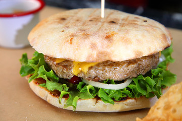 Burger with meat and vegetables. Double cheese burger. Hot burger in a burning sauce. 