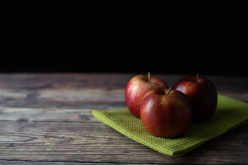 Red apples on the green cloth on the wooden table picture.