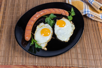 Fried eggs prepared sunny side up and wiener on dish