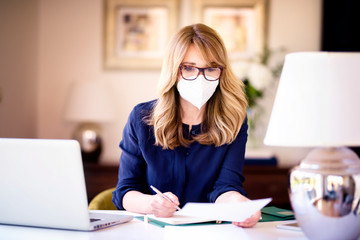 Middle aged woman wearing face mask for prevention while working from home